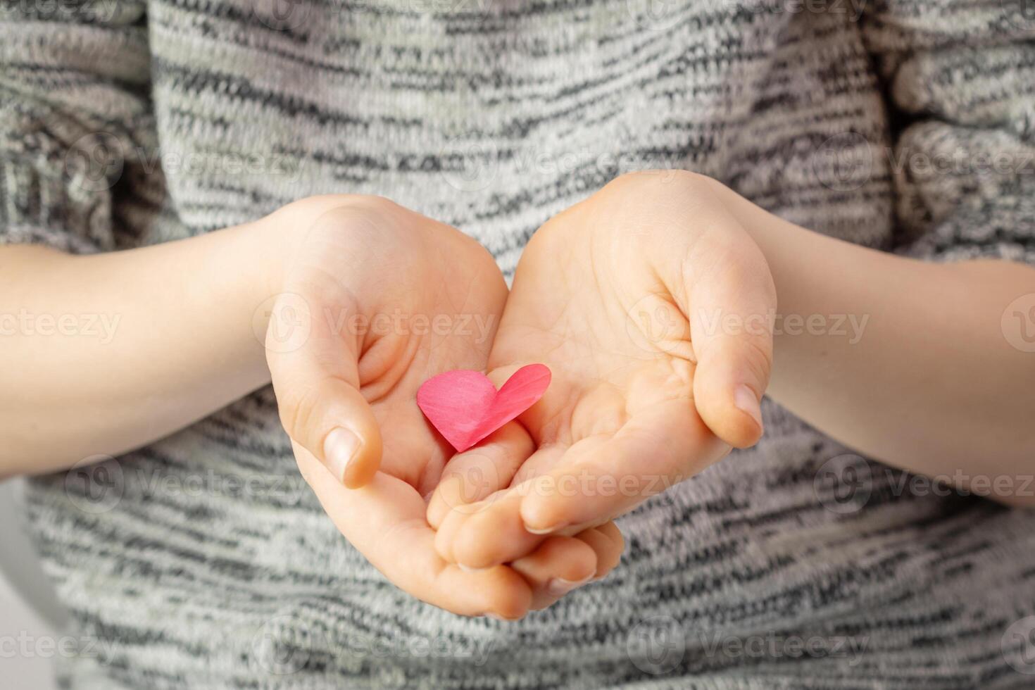para niños manos sostener un corazón dibujado, cortar fuera y pintado rojo foto