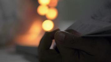 mãos de mulher virando as páginas de um livro à noite video