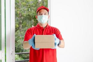 un repartidor vestido con una camisa roja y un sombrero sostiene una caja de paquetería foto