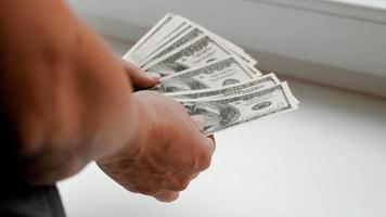 uma pessoa considera o dinheiro muito alto. mãos femininas contando notas de cem dólares, pagamento em dinheiro, o conceito de investimento, sucesso, crescimento na carreira video