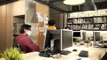 afroamerikanische arbeiterin mit gesichtsmaske kommt zur arbeit und begrüßt kollegen im geschäftsbüro, covid-19-schutz durch geräumte trennwand, soziale distanzierung, pandemische gesundheit, krankheitsprävention. video