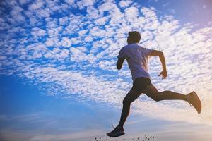 Silhouette of young man running sprinting on road. Fit runner fitness runner during outdoor workout with sunset background. photo