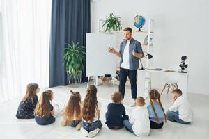 explicando la lección y usando el tablero. grupo de niños estudiantes en clase en la escuela con el maestro foto