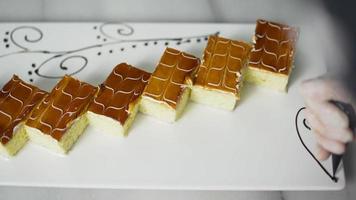 lo chef decora il piatto da dessert. dolce a trecce. chef disegno ornamento con salsa di cioccolato sul bordo del piatto da dessert. video