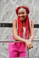 Fashionable african american girl at pink pants and red dreads posed outdoor. photo
