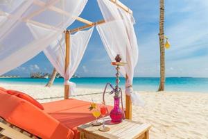 cachimba de copa de cóctel en carpa, dosel en el resort de playa de mar, idílico estilo de vida de ocio recreativo de verano. vacaciones de lujo, relajación del estado de ánimo árabe oriental. verano junto a la playa tumbonas salón café al aire libre foto
