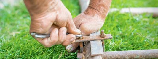 Elderly man twists the nut by wrench photo