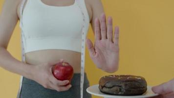 as mulheres magras recusam junk food ou alimentos não saudáveis, como rosquinhas, e escolhem alimentos saudáveis, como maçã verde. boa saúde alimentar e dieta. perder peso, equilibrar, controlar, reduzir gordura, calorias, rotinas video