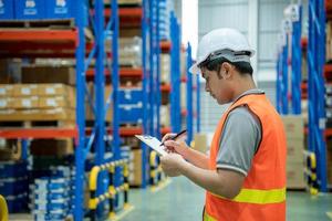 Asian male factory manager inspects the goods in the warehouse and check stock product. Transport logistic business shipping and delivery to customers quickly through a freight forwarding company. photo