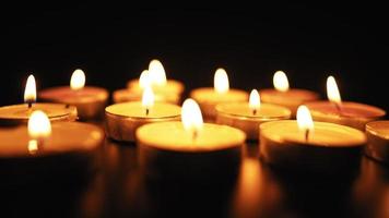 Kerzen brennen mit einer weichen gelben Flamme im Dunkeln. religion und bestattungskonzept. Trauer um die Toten. Zeitlupe. video