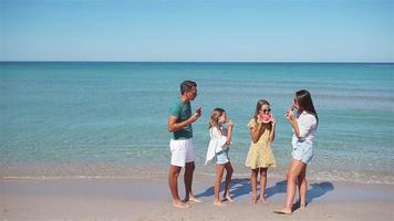 Happy family eating watermelon on the beach. video