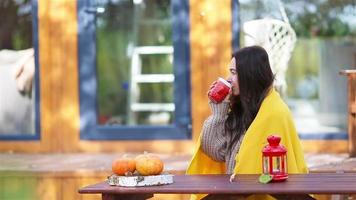 mujer joven feliz con teléfono y tomando café sentado en la mesa de madera al aire libre video