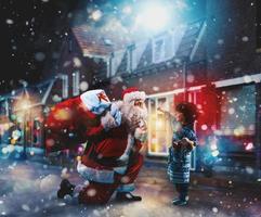 Santa Claus is giving a present for Christmas to a little boy photo