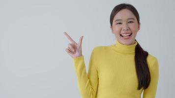 Portrait asian beautiful girl pointing blank space isolated background. Happy woman pointing on something. young female standing pointing finger sideways, billboard, introduction, advertisement, space video