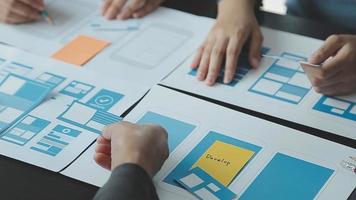 feche o brainstorming do desenvolvedor de ux e do designer de interface do usuário sobre o design de wireframe da interface de aplicativo móvel na mesa com resumo do cliente e código de cores no escritório moderno. agência de desenvolvimento digital criativa video