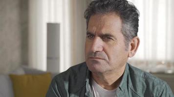 fermer coup de réfléchi mature adulte homme avec gris cheveux séance seul à Accueil en pensant à propos la vie seule. video