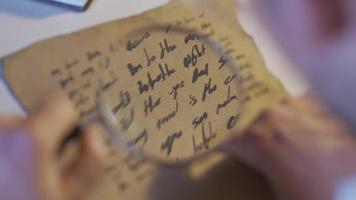 epigrafista examinando letra escrito en histórico medieval alfabeto. molesto a leer el escritos con un aumentador vaso, el epigrafista traduce el carta. video
