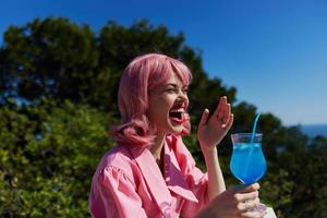 alegre mujer Bebiendo un cóctel en el terraza Bebiendo alcohol foto