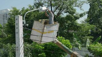 Worker on height lifting platform installing new street light bulb. Electrician work service mounting street light. Replacement of old  lamps with new LED lighting. Technician light repair light pole video