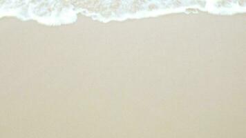 view to white sand beach surface texture with sea wave hit the beach in summer sunny sunshine day,wave swept towards the shore with white bubble waves, summer holiday vacation video