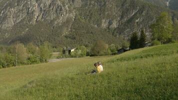 une garçon et fille sont séance dans le herbe champ sur le Montagne video