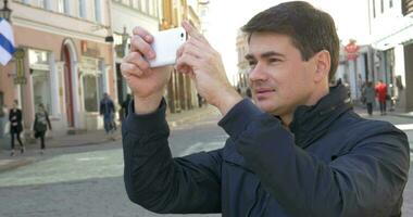 hombre con teléfono inteligente haciendo disparos de edificios video