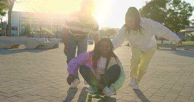 Multiethnic group of young happy friends having fun and skating down the street in slow motion. video