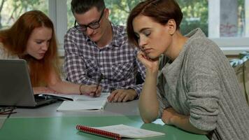 Young female student looking tired and confused while writing in her textbook video