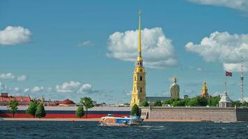 Russia, St. Petersburg, 30 July 2023, Famous spire of the Peter and Paul Cathedral at sunny clear weather, walls of fortress, touristic boat with foil video