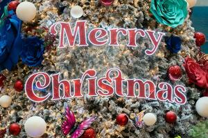 Close-up view of the Merry Christmas wording and ornaments hanging on the Christmas tree. photo