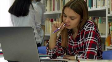 femelle étudiant garde stylo dans sa bouche à le bibliothèque video