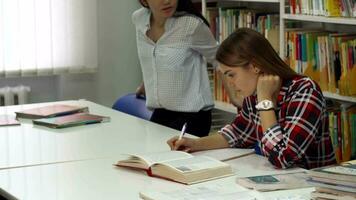 femelle étudiant est assis vers le bas près sa camarade de classe à le bibliothèque video