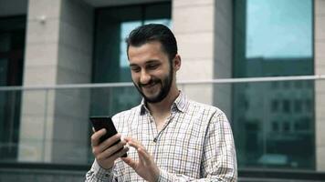 aantrekkelijk Kaukasisch jong Mens op zoek Bij smartphone video