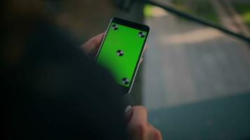 traseiro sobre ombro Visão empresária usando Smartphone verde tela croma chave Móvel brincar desconhecido menina mulher aguarde telefone com cópia de espaço celular dispositivo o negócio aplicativo conectados ordem dentro cidade ao ar livre video