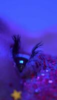 extrême fermer vue de femelle œil avec brillant maquillage avec scintille illuminé rose bleu néon lumière video