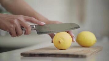 Female Hand Slices Yellow Lemon with Knife On a Wooden Cutting Board In the Kitchen video