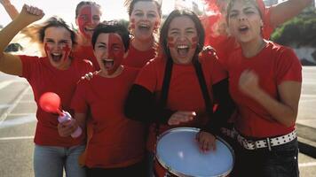 femmina calcio fan esultante mentre Guardando un' calcio gioco a il stadio - donne con dipinto viso e megafono incoraggiando loro squadra - sport divertimento concetto video