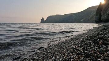 Sea beach horizon. Sea waves with soft, foamy waters washing multicolored pebbles on a beach during sunset. Nobody. Holiday recreation concept. Abstract nautical summer ocean sunset nature Slow motion video
