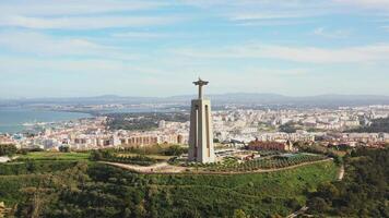 Lisbon, Portugal 27 June 2023 Christ the King, Almada, Portugal. Panorama Lisbon city with beautiful landmarks. Aerial view Tagus River and 25 de Abril Bridge in background blue sky video