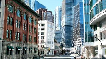 beautiful view of downtown Vancouver tall buildings skyscrapers old and new street lights cars real people life in big city glass office spaces restaurants cafes traffic lights intersections blue sky video