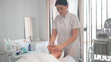 Cosmetologist wiping face of customer in beauty clinic video
