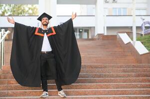Handsome indian graduate in graduation glow with diploma. photo