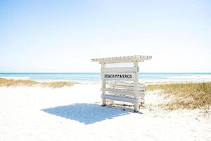White Wooden Beach Sign with Blue Sea and Sky photo