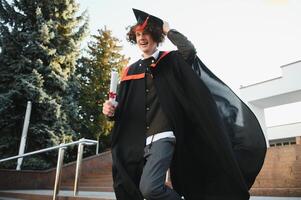 Portrait of a confident and joyful young graduate with a diploma. Man is ready for the next step in his life. photo
