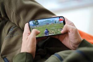 PUBG PlayerUnknowns Battlegrounds mobile iOS game on iPhone 15 smartphone screen in male hands during mobile gameplay photo