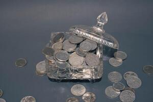 dinero monedas en claro vaso en oscuro gris fondo, negocio inversión crecimiento concepto, ahorro concepto, moneda en claro tarro terminado oscuro gris antecedentes. Copiar espacio. foto