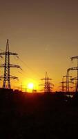 industriale zona a tramonto. alta tensione elettrico Linee vicino fabbrica con tubi con sporco Fumo nel il sera. buio sagome di energia stazione. verticale video