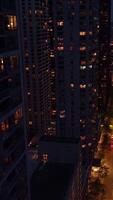bien iluminado calle de chicago céntrico a noche. zumbido imágenes descendente entre el maravilloso rascacielos terminado el ocupado la carretera. vertical video