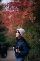 Asian woman in Japan's fall beauty, a cheerful holiday portrait in Kyoto. Vibrant foliage, friends, and smiles by the lake create a joyful and scenic atmosphere. photo