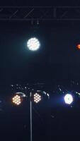 buio palcoscenico con colorato faretti o parecchi luminosa proiettori. diverso proiettori con illuminazione effetti su scena nel il sera. verticale video